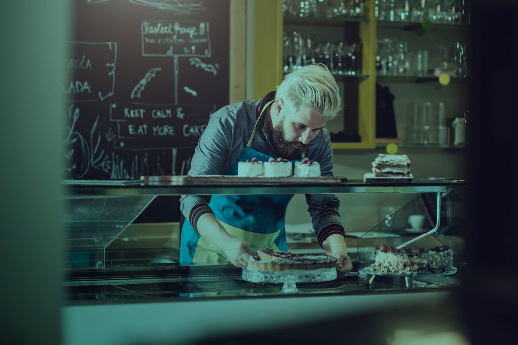 Baker setting a cake in a window display