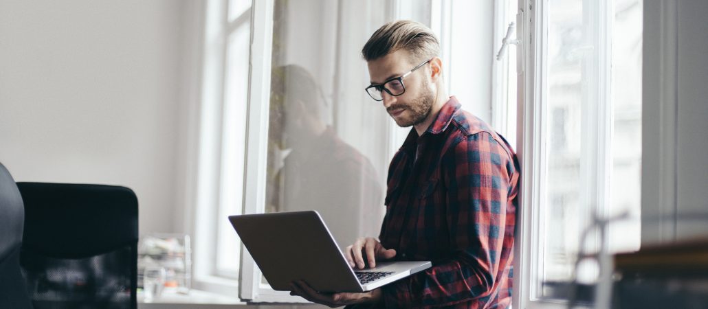 Male business owner standing with laptop in hand 