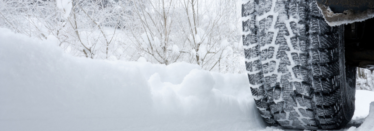 Close-up of a rear black tire in the snow creating tracks