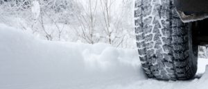 Close-up of a rear black tire in the snow creating tracks