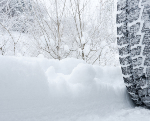 Close-up of a rear black tire in the snow creating tracks