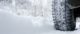 Close-up of a rear black tire in the snow creating tracks