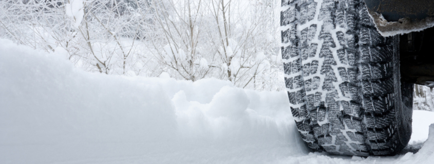 Close-up of a rear black tire in the snow creating tracks