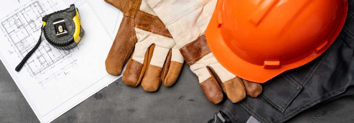 Construction helmet, gloves, and measuring tape on table.