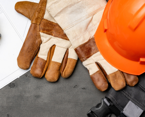 Construction helmet, gloves, and measuring tape on table.